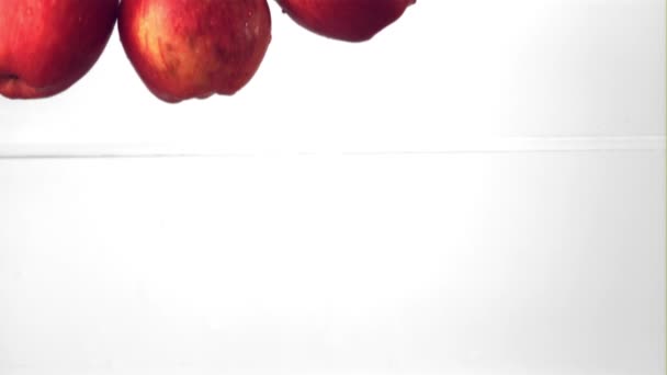 Супер повільний рух червоних яблук потрапляють у воду з бризками. Знято на високошвидкісній камері зі швидкістю 1000 к/с . — стокове відео