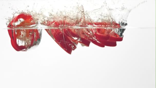Super lambat gerak potongan merica merah manis jatuh ke dalam air dengan splashes.Filmed pada 1000 fps. — Stok Video