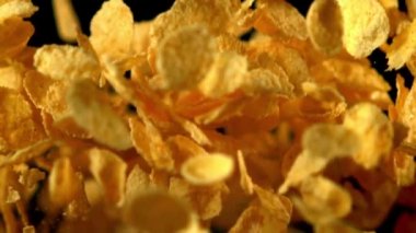 Süper yavaş çekim mısır gevrekleri siyah arka plana doğru havalanır. Çekim 1000 fps 'de..