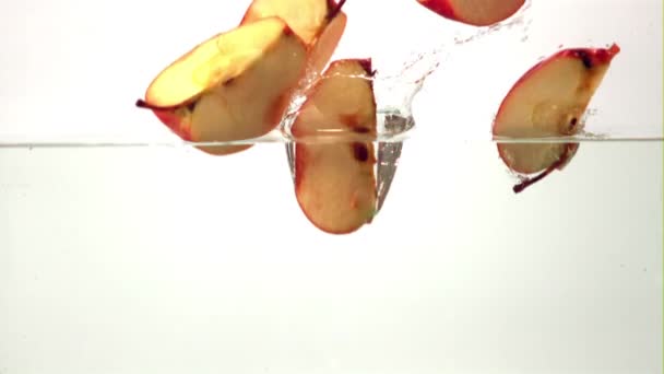 Сверхмедленные куски спелого яблока падают в воду с брызгами. Снято на высокоскоростную камеру со скоростью 1000 кадров в секунду. — стоковое видео