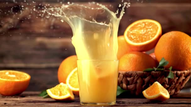 Super slow motion i ett glas med apelsinjuice droppar en bit apelsin med stänk. Inspelning vid 1000 fps. — Stockvideo