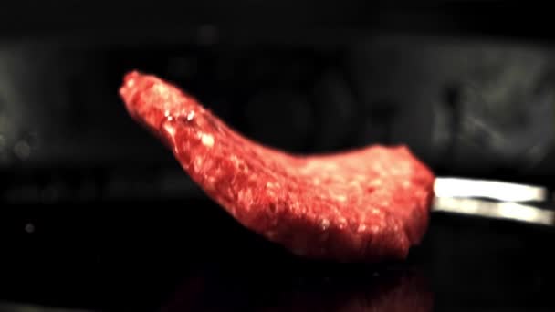 The super slow motion raw burger falls on the pan with a splash of oil.Filmed at 1000 fps. — Stock Video