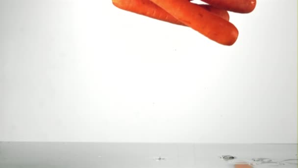 Суперзамедленная морковь падает в воду с брызгами. Снято на высокоскоростную камеру со скоростью 1000 кадров в секунду. — стоковое видео