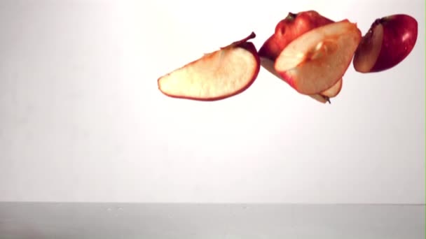 Trozos de manzana madura en cámara súper lenta caen al agua con salpicaduras. Filmado en una cámara de alta velocidad a 1000 fps. — Vídeo de stock