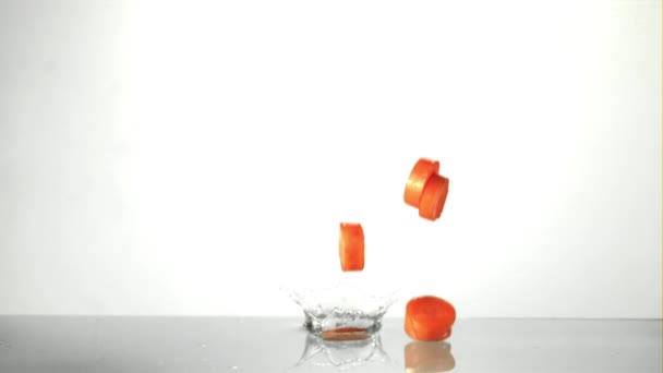 Pezzi super lenti di carota cadono in acqua con schizzi. Girato su una telecamera ad alta velocità a 1000 fps. — Video Stock