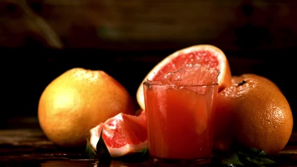 Super slow motion in een glas met grapefruitsap valt een stuk grapefruit met spray. Gefilmd met 1000 fps. — Stockvideo
