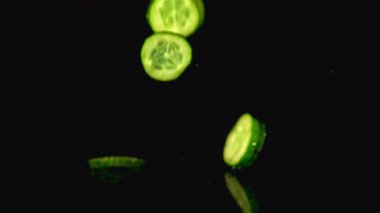 Süper yavaş hareket eden taze salatalık parçaları suya dökülüyor. 1000 fps hızla yüksek hızlı bir kamerayla çekildi..