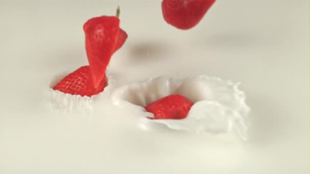 Super-Zeitlupe Hälften von Erdbeeren fallen mit Spritzern in Milch. Gefilmt mit einer Hochgeschwindigkeitskamera bei 1000 fps — Stockvideo
