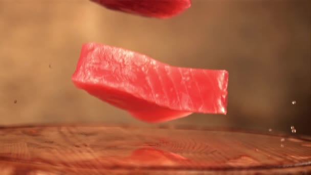 Mouvement super lent avec des éclaboussures d'eau tombant des steaks de thon sur une planche à découper en bois. Filmé par une caméra haute vitesse à 1000 ips. — Video