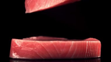 Süper yavaş çekim çiğ ton balığı bifteği masanın üzerine düşer. 1000 fps hızla yüksek hızlı bir kamerayla çekildi..