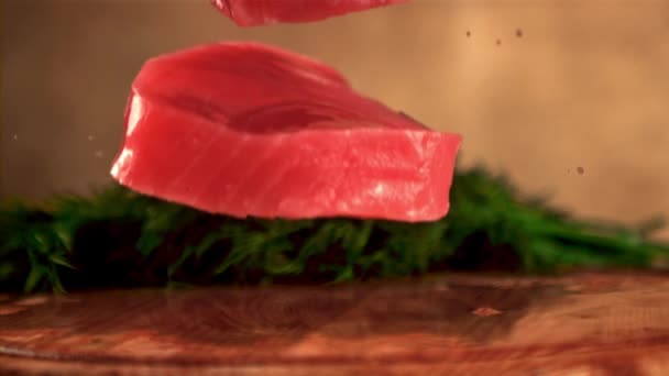 Супер медленное движение стейк сырого тунца падает на разделочную доску с укропом. Снято на высокоскоростную камеру со скоростью 1000 кадров в секунду. — стоковое видео