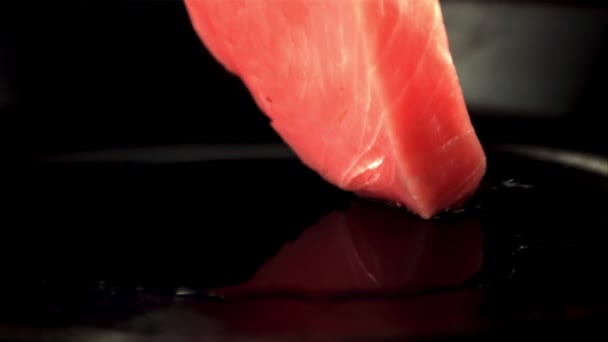 O bife de atum cru super lento cai em uma panela com um toque de óleo. Filmado em uma câmera de alta velocidade a 1000 fps. — Vídeo de Stock
