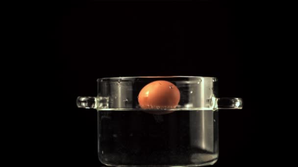 Super cámara lenta huevo cae en una sartén con spray de agua. Filmado en una cámara de alta velocidad a 1000 fps. — Vídeo de stock
