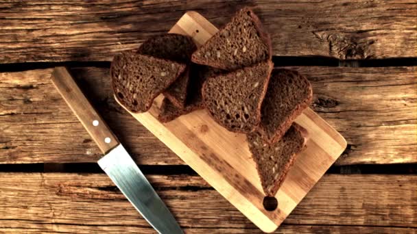 Super wolne kawałki pachnącego chleba spadają na deskę do krojenia. Nagrywane na szybkiej kamerze z prędkością 1000 fps. — Wideo stockowe