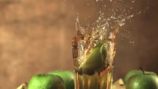 Super slow motion een stuk verse appel met spetters valt in een glas sap. Gefilmd op een hoge snelheidscamera met 1000 fps. — Stockvideo