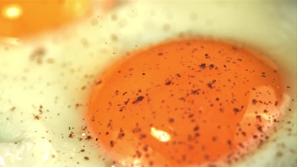 Super rallentatore pepe macinato cade sull'uovo fritto. Girato su una telecamera ad alta velocità a 1000 fps. — Video Stock