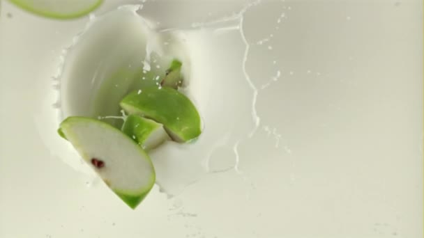Super zpomalené kousky jablek padají do mléka s cákáním. Natočeno na vysokorychlostní kameře rychlostí 1000 snímků za sekundu — Stock video