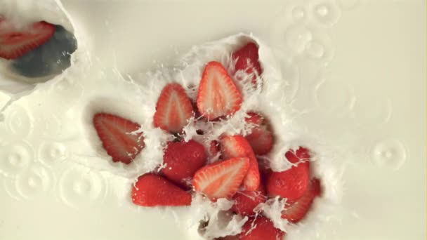 Trozos de fresas de cámara súper lenta caen en la leche. Filmado en una cámara de alta velocidad a 1000 fps — Vídeos de Stock