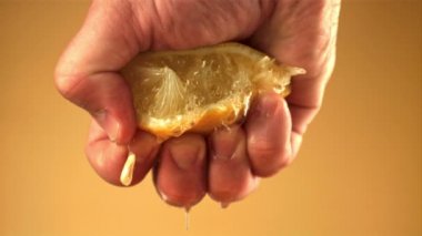Süper yavaş çekimde adamın eli limonun suyunu sıkıyor. 1000 fps hızla yüksek hızlı bir kamerayla çekildi..