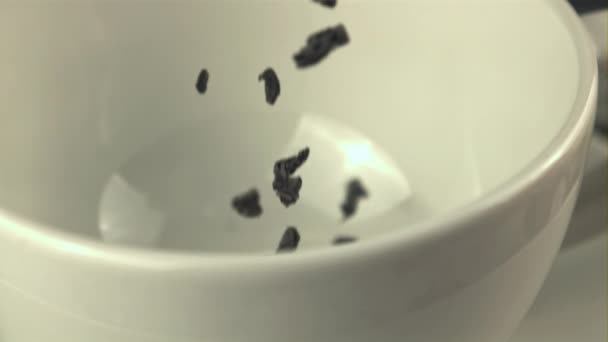 Les feuilles de thé sèches au ralenti super tombent dans la tasse blanche. Filmé par une caméra haute vitesse à 1000 ips. — Video