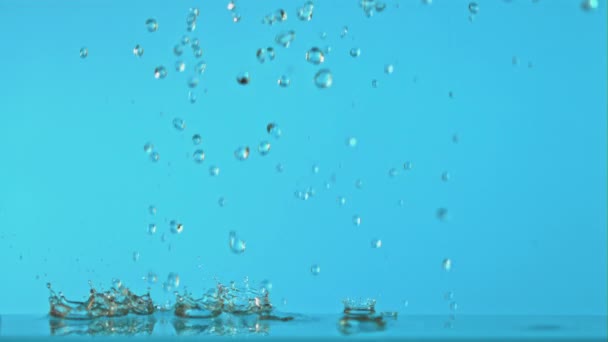 Süper yavaş çekimde su damlacıkları mavi arka plana düşer. 1000 fps hızla yüksek hızlı bir kamerayla çekildi.. — Stok video
