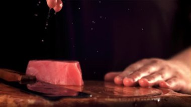 Adamın süper yavaş çekim kolu kesme tahtasına çiğ ton balıklı biftek fırlatır. 1000 fps hızla yüksek hızlı bir kamerayla çekilir..