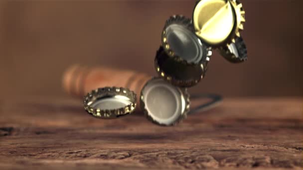 Super powolne pokrywy z butelek po piwie spadają na drewniany stół. Nagrywane na szybkiej kamerze z prędkością 1000 fps. — Wideo stockowe