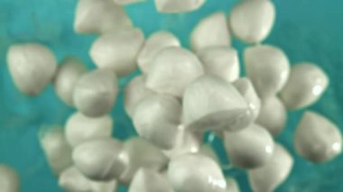 Mozzarella topları uçar ve mavi arka plana düşer. 1000 fps 'de yüksek hızlı bir kamerayla çekildi. Yüksek kaliteli FullHD görüntüler