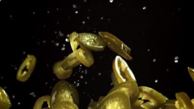 Turşulu jalapenolar uçar ve siyah arka planda düşerler. 1000 fps 'de yüksek hızlı bir kamerayla çekildi. Yüksek kaliteli FullHD görüntüler