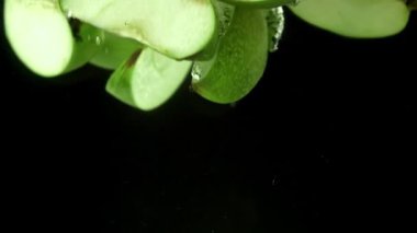 Yeşil elma parçaları suyun altına düşer. 1000 fps 'de yüksek hızlı bir kamerayla çekildi. Yüksek kaliteli FullHD görüntüler