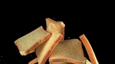 Taze ekmek parçaları siyah arka planda uçuyor. 1000 fps 'de yüksek hızlı bir kamerayla çekildi. Yüksek kaliteli FullHD görüntüler