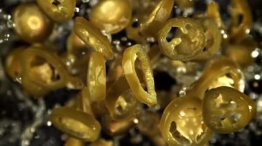 Turşulu jalapenolar uçar ve siyah arka planda düşerler. 1000 fps 'de yüksek hızlı bir kamerayla çekildi. Yüksek kaliteli FullHD görüntüler