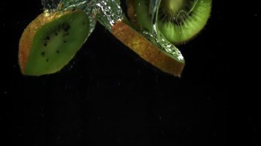 Dilimlenmiş kivi siyah arka planda suyun altına düşüyor. 1000 fps 'de yüksek hızlı bir kamerayla çekildi. Yüksek kaliteli FullHD görüntüler