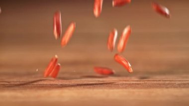 Kırmızı pirinç ahşap bir masaya düşer. 1000 fps 'de yüksek hızlı bir kamerayla çekildi. Yüksek kaliteli FullHD görüntüler