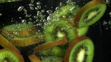 Dilimlenmiş kivi siyah arka planda suyun altına düşüyor. 1000 fps 'de yüksek hızlı bir kamerayla çekildi. Yüksek kaliteli FullHD görüntüler