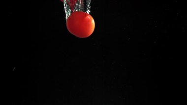 Siyah arka planda suyun altına düşen taze domatesler. 1000 fps 'de yüksek hızlı bir kamerayla çekildi. Yüksek kaliteli FullHD görüntüler