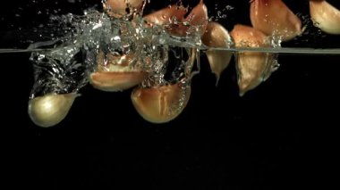 Sarımsak karanfilleri suyun altına düşer. 1000 fps 'de yüksek hızlı bir kamerayla çekildi. Yüksek kaliteli FullHD görüntüler