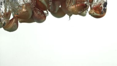 Sarımsak karanfilleri suyun altına düşer. 1000 fps 'de yüksek hızlı bir kamerayla çekildi. Yüksek kaliteli FullHD görüntüler