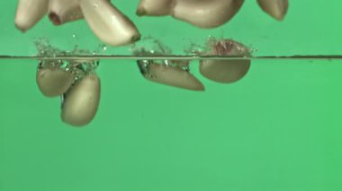 Sarımsak karanfilleri suyun altına düşer. 1000 fps 'de yüksek hızlı bir kamerayla çekildi. Yüksek kaliteli FullHD görüntüler