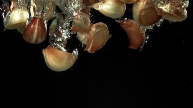 Sarımsak karanfilleri suyun altına düşer. 1000 fps 'de yüksek hızlı bir kamerayla çekildi. Yüksek kaliteli FullHD görüntüler