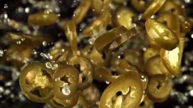 Turşulu jalapenolar uçar ve siyah arka planda düşerler. 1000 fps 'de yüksek hızlı bir kamerayla çekildi. Yüksek kaliteli FullHD görüntüler