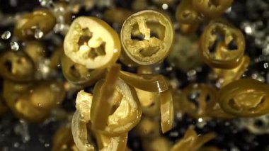 Turşulu jalapenolar uçar ve siyah arka planda düşerler. 1000 fps 'de yüksek hızlı bir kamerayla çekildi. Yüksek kaliteli FullHD görüntüler