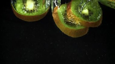 Dilimlenmiş kivi siyah arka planda suyun altına düşüyor. 1000 fps 'de yüksek hızlı bir kamerayla çekildi. Yüksek kaliteli FullHD görüntüler