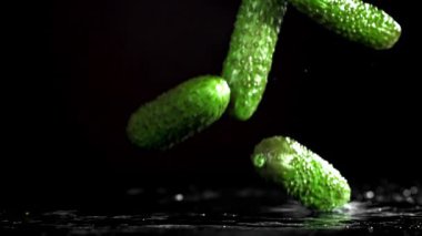 Salatalıklar siyah arka planda masaya düşer. 1000 fps 'de yüksek hızlı bir kamerayla çekildi. Yüksek kaliteli FullHD görüntüler