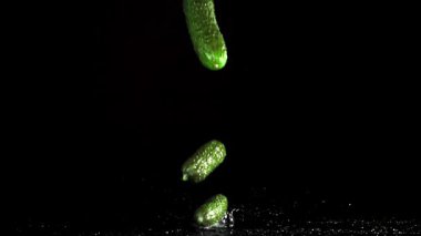 Salatalıklar siyah arka planda masaya düşer. 1000 fps 'de yüksek hızlı bir kamerayla çekildi. Yüksek kaliteli FullHD görüntüler