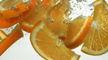 Portakal parçaları beyaz arka planda suyun altına düşüyor. 1000 fps 'de yüksek hızlı bir kamerayla çekildi. Yüksek kaliteli FullHD görüntüler