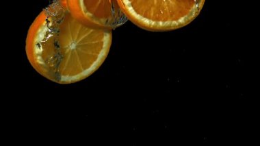 Portakal dilimleri siyah arka planda suyun altına düşüyor. 1000 fps 'de yüksek hızlı bir kamerayla çekildi. Yüksek kaliteli FullHD görüntüler