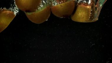 Dilimlenmiş kivi siyah arka planda suyun altına düşüyor. 1000 fps 'de yüksek hızlı bir kamerayla çekildi. Yüksek kaliteli FullHD görüntüler