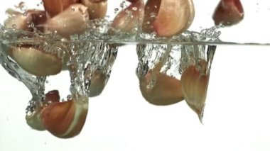 Sarımsak karanfilleri suyun altına düşer. 1000 fps 'de yüksek hızlı bir kamerayla çekildi. Yüksek kaliteli FullHD görüntüler