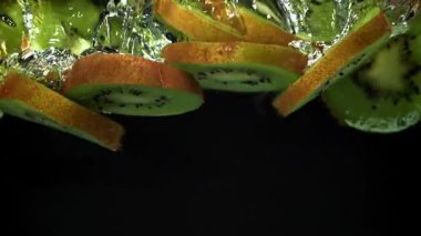 Dilimlenmiş kivi siyah arka planda suyun altına düşüyor. 1000 fps 'de yüksek hızlı bir kamerayla çekildi. Yüksek kaliteli FullHD görüntüler